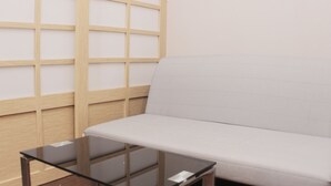 A room with a white sofa, a glass table, and a wooden partition with a grid pattern.