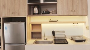 A kitchen with a stainless steel refrigerator, a sink, and a countertop with a kettle, a pot, and a coffee maker. - Minimalist And Cozy Studio At Vasanta Innopark Apartment (Cikarang)