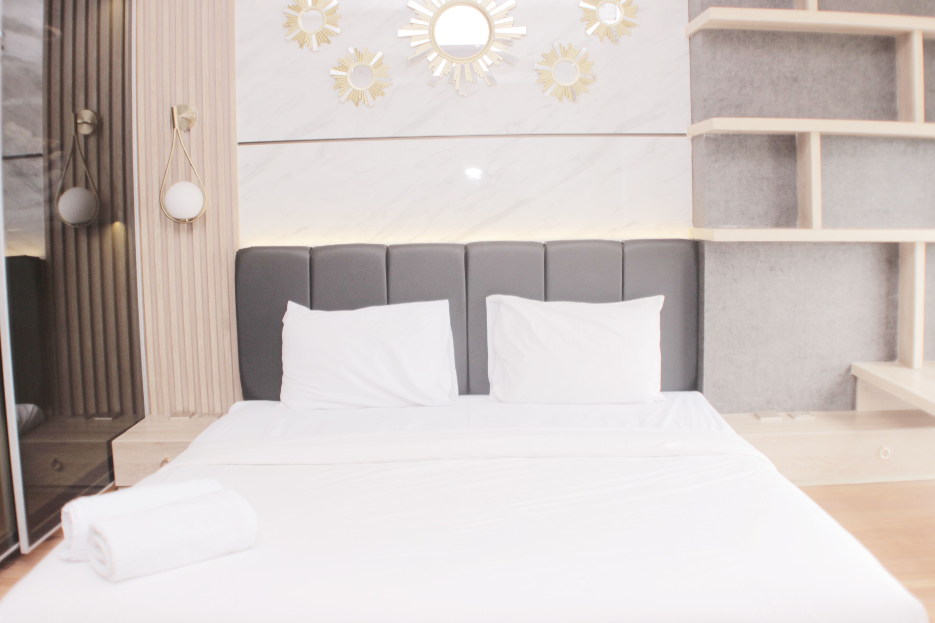 Ett modernt hotellrum med en stor säng, en sänggavel och en hylla som är monterad på väggen.