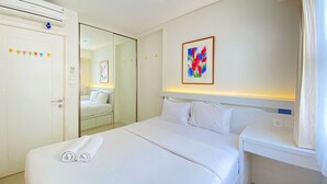 Ein Hotelzimmer mit Bett, Nachttisch, Kleiderschrank und Spiegel.