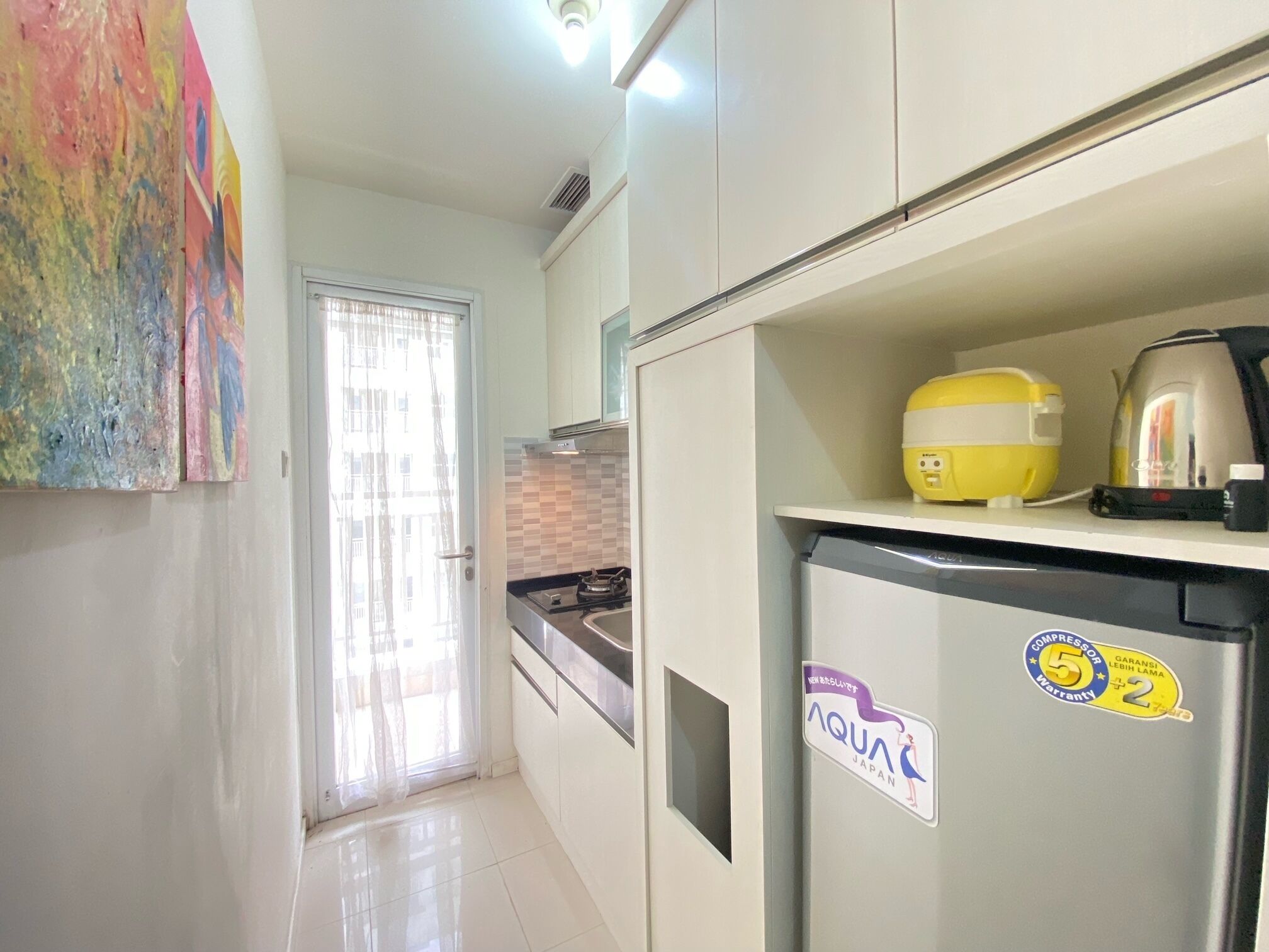A kitchen with a refrigerator, a yellow appliance, and a kettle.
