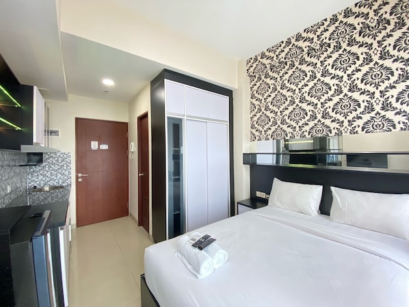 A hotel room with a bed, a wardrobe, a bathroom, and a kitchenette.