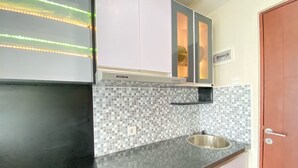A kitchen with a tiled backsplash, a stainless steel sink, and a built-in oven. - Affordable Studio Room At Taman Melati Jatinangor Apartment (Hegarmanah)