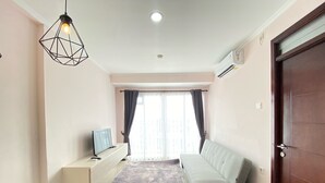 Un salon moderne avec un canapé, un téléviseur à écran plat, un luminaire décoratif et une grande fenêtre avec des rideaux.