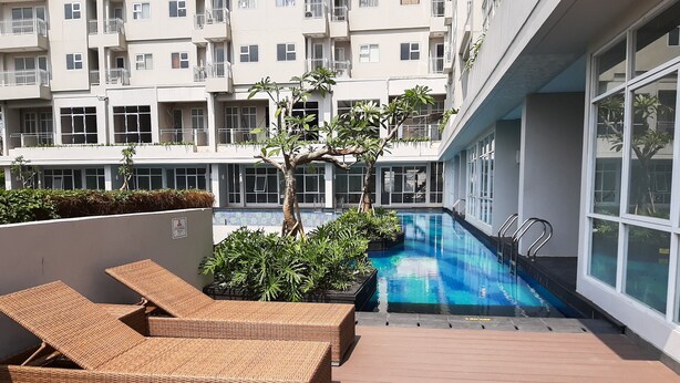 A rooftop pool area with lounge chairs and a small tree. - Minimalist And Comfy Studio At Bintaro Icon Apartment (South Tangerang)