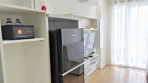 Een moderne keuken met een zwarte koelkast, een Panasonic TV en een plank met een Travelio aanvullende etens- en drankjesdoos.