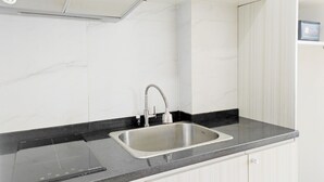Een moderne keuken met een roestvrijstalen spoelbak, een zwart aanrecht, witte kasten en een inbouw afzuigkap.