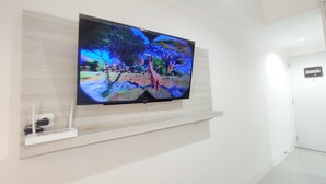 A flat-screen TV mounted on a wall in a hotel room. - Nice Cozy Studio At Paltrow City Apartment (Semarang)