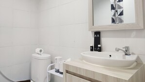 A modern bathroom with a white sink, a toilet, and a mirror. - Nice Cozy Studio At Paltrow City Apartment (Semarang)