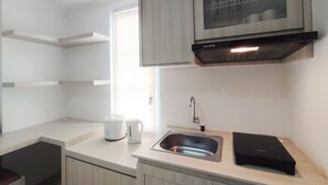 A modern kitchen with a built-in oven, a sink, and a countertop. - Nice Cozy Studio At Paltrow City Apartment (Semarang)