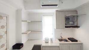 A compact kitchen with a built-in air conditioner, a sink, and a countertop with a kettle and a coffee maker. - Nice Cozy Studio At Paltrow City Apartment (Semarang)