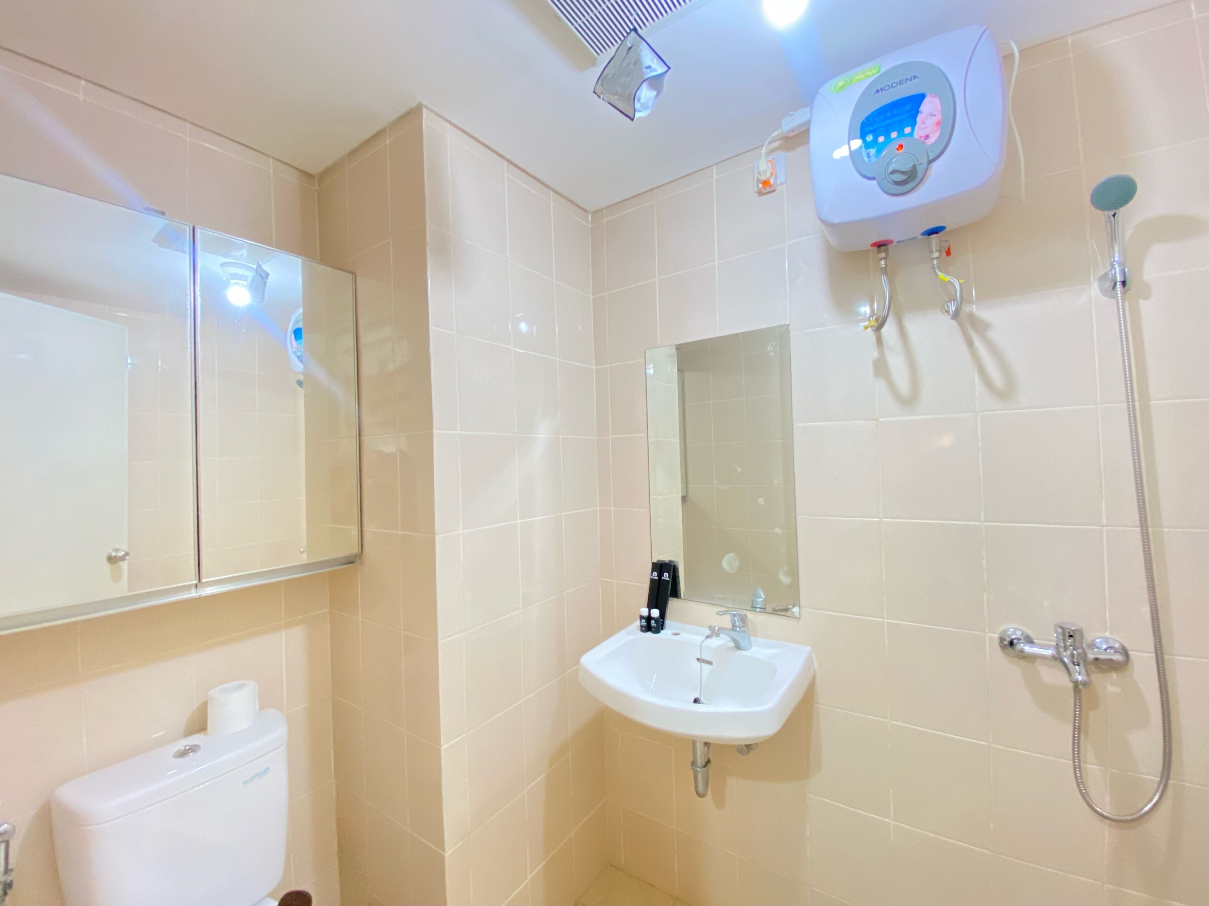 A bathroom with a toilet, sink, mirror, and shower.