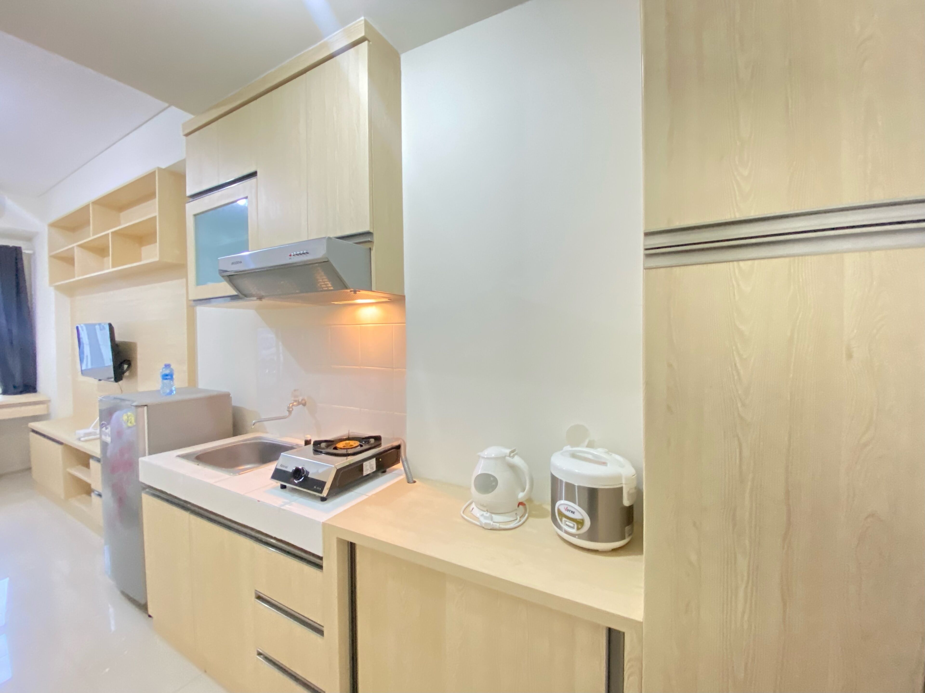 Une cuisine moderne avec des meubles en bois, un four encastré, une bouilloire et une machine à café.