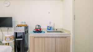 Een compacte keuken met een waterdispenser, een klein fornuis en een spoelbak.