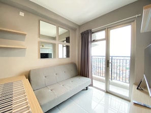 A modern living room with a grey sofa, a wooden coffee table, and a large window with a view of the city.