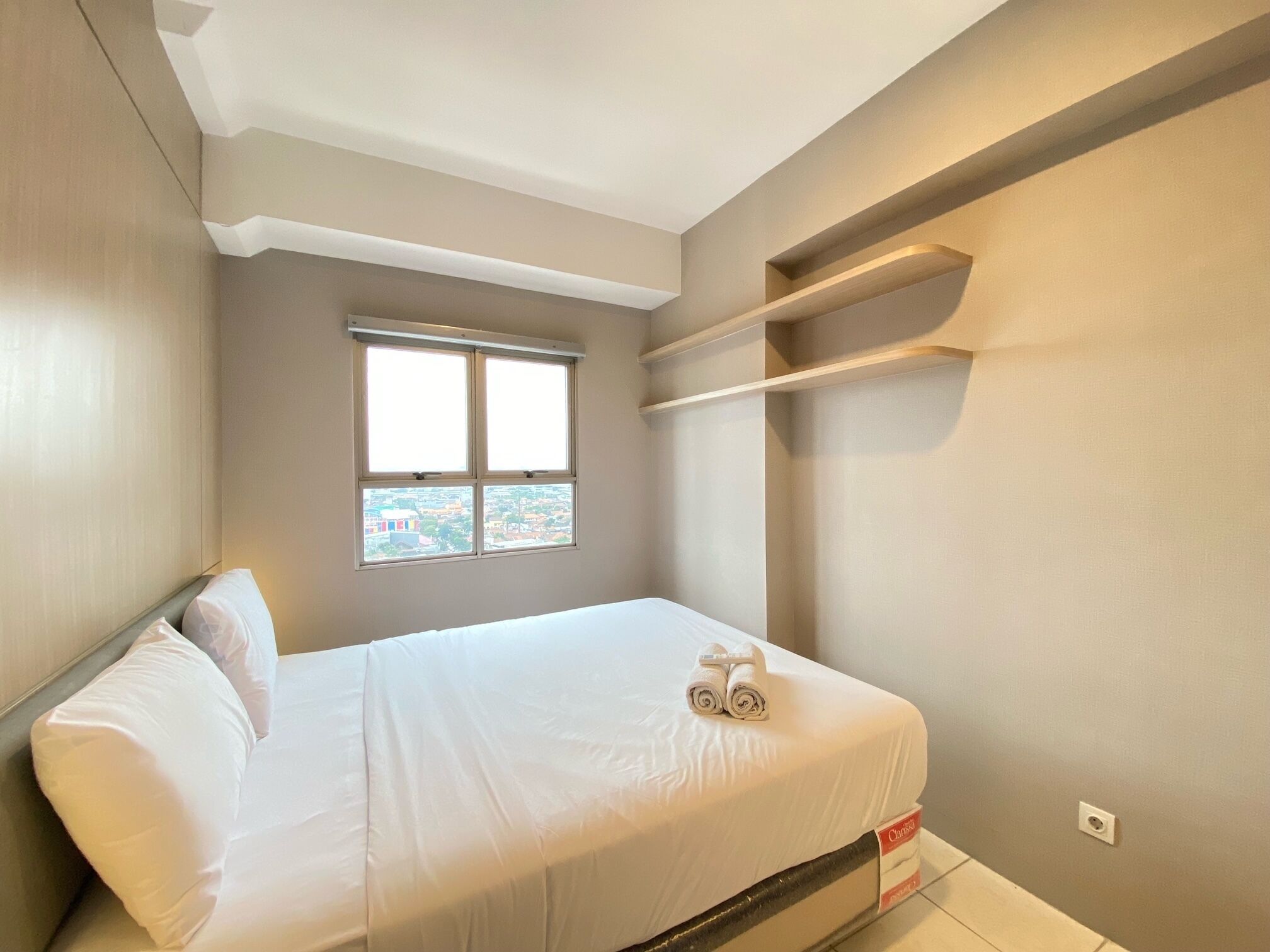 A bedroom with a bed, a window, and a built-in shelf.