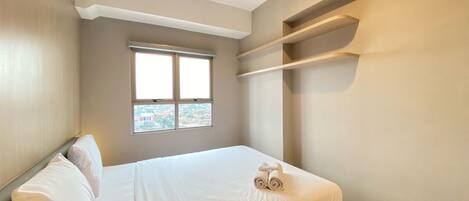 A bedroom with a bed, a window, and a built-in shelf.