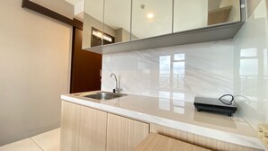 A modern kitchen with a marble countertop, wooden cabinets, and a built-in sink. - Well Furnished And Private 2Br Mekarwangi Square Cibaduyut Apartment (Bandung)
