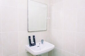 A bathroom with a white sink, a mirror, and two black dispensers on the wall. - Warm And Minimalist 3Br Apartment At M-Town Residence (Gading Serpong)