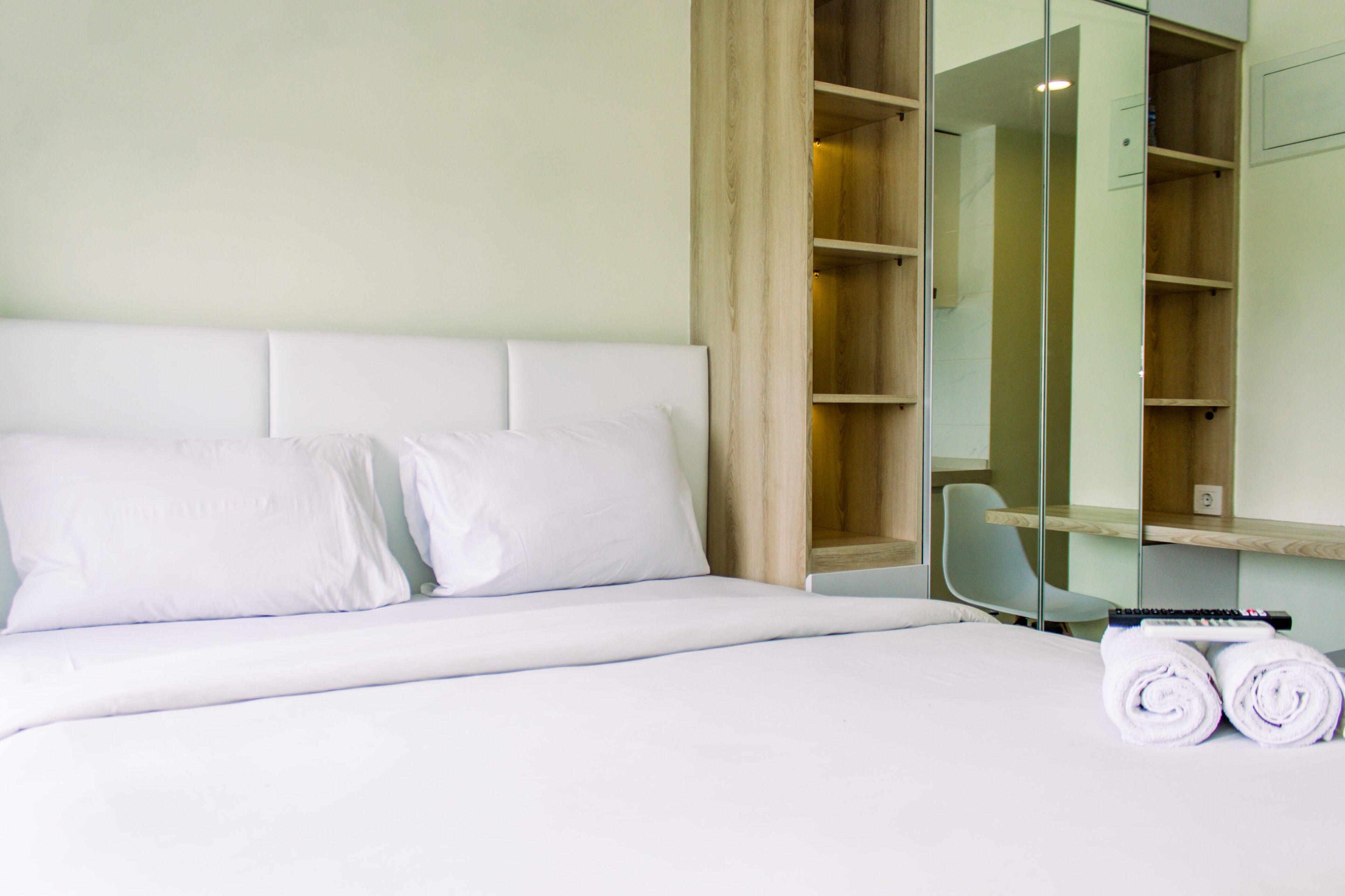 Een hotelkamer met een groot bed, een spiegel, een houten garderobe en een stoel.