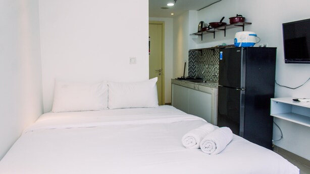 Quarto de hotel com cama, frigorífico, micro-ondas e pequena cozinha equipada.