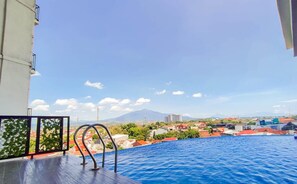 Una piscina al aire libre con vistas a un paisaje urbano y una montaña en la lejanía.