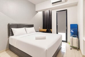 Habitación de hotel moderna con cama, mesita de noche, dispensador de agua y puerta.