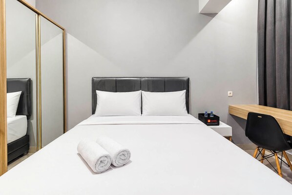 Una habitación de hotel con una cama, un escritorio, una silla y un espejo.