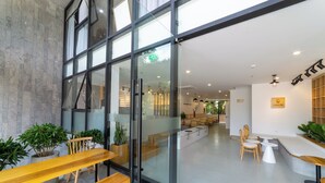 Een modern interieur met glazen deuren die leiden naar een zithoek met houten banken en potplanten.