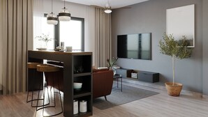 Een moderne woonkamer met een televisie, een salontafel, een bank en een eethoek met een bar.