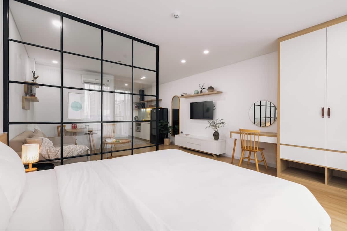 Um quarto moderno com uma cama grande, uma escrivaninha, uma cadeira, um guarda-roupa e uma televisão.