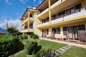 A multi-story hotel with balconies, a garden area, and outdoor seating. - Residence Mariù (Malcesine)