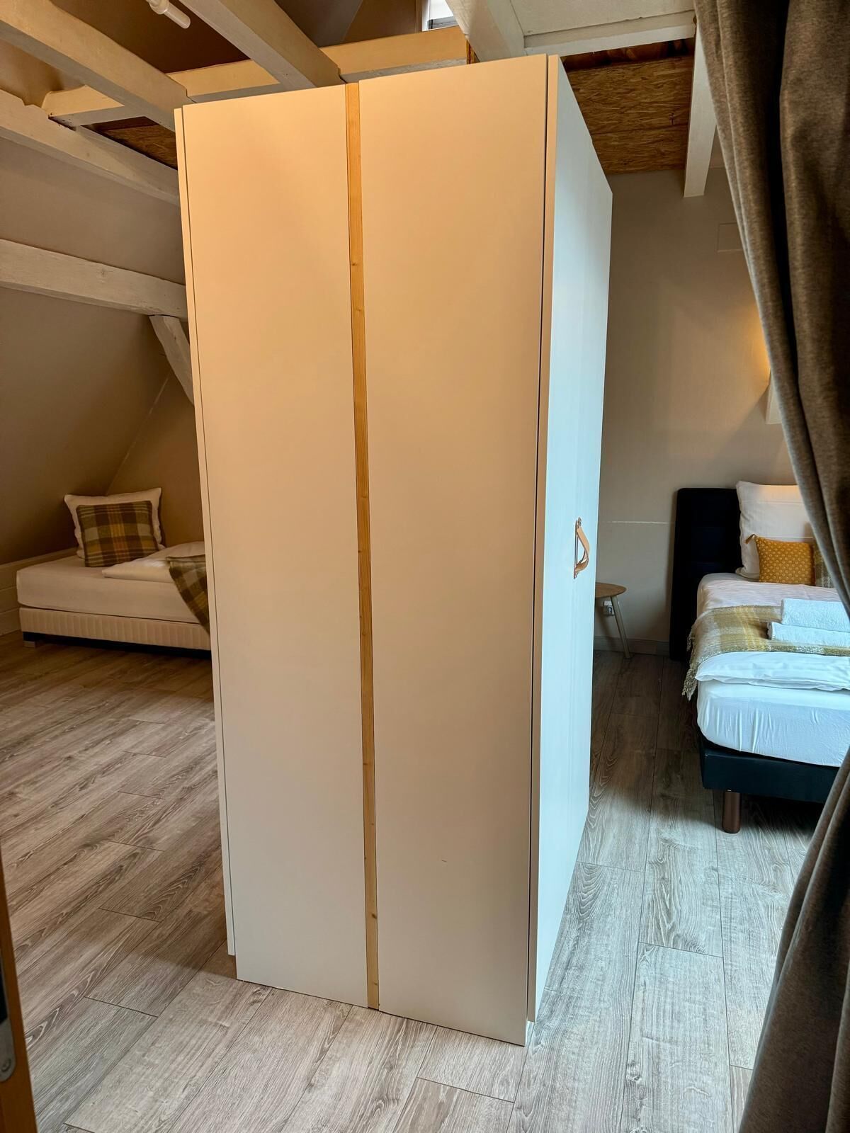 Une chambre avec une grande armoire, un lit et une petite table.
