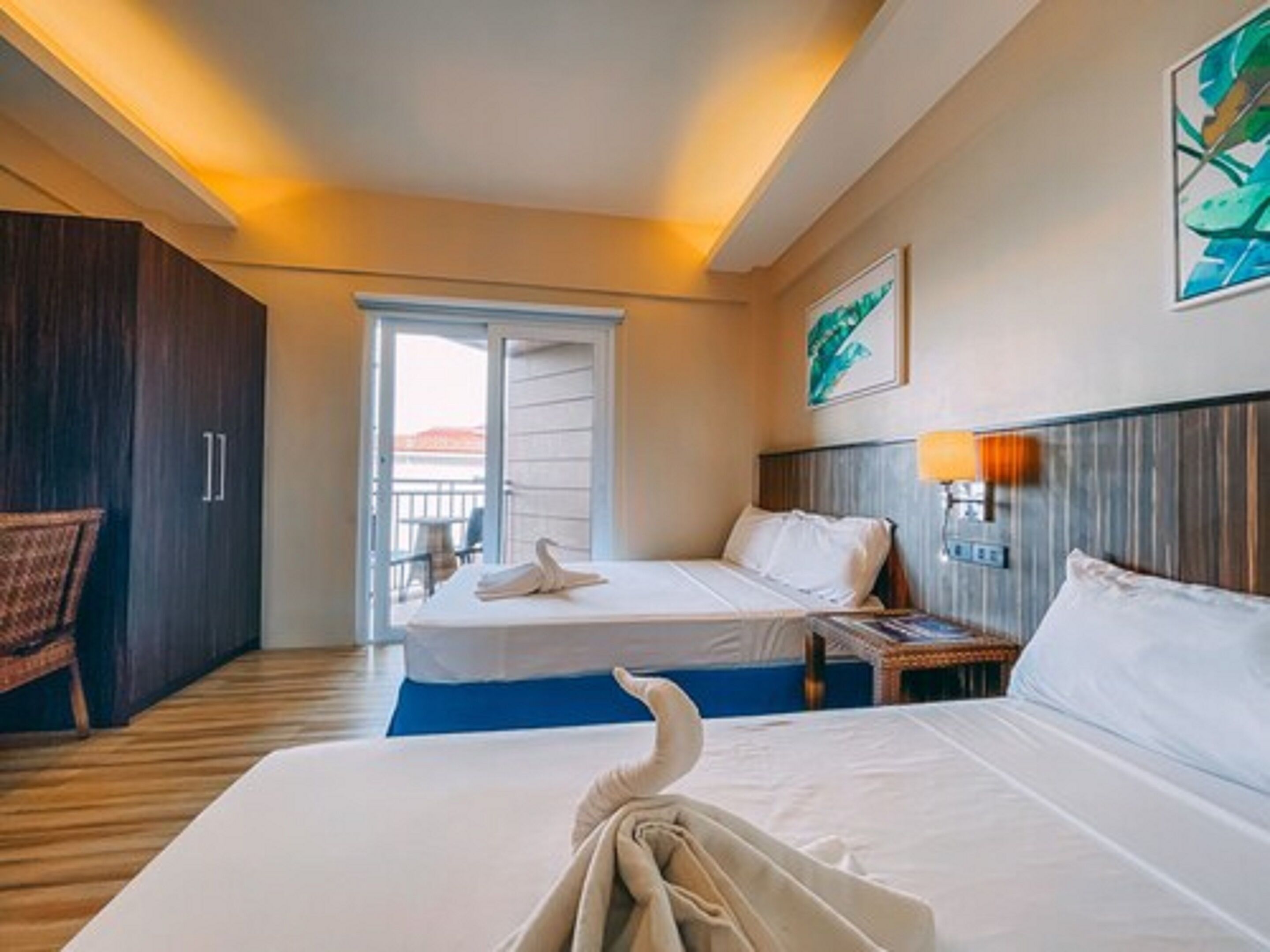Une chambre d’hôtel comprenant un lit, une table de chevet, une lampe, une chaise et une porte donnant sur un balcon.