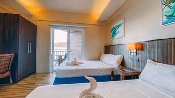 Une chambre d’hôtel comprenant un lit, une table de chevet, une lampe, une chaise et une porte donnant sur un balcon.