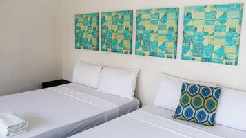 A hotel room with two beds, white bedding, and a patterned pillow.