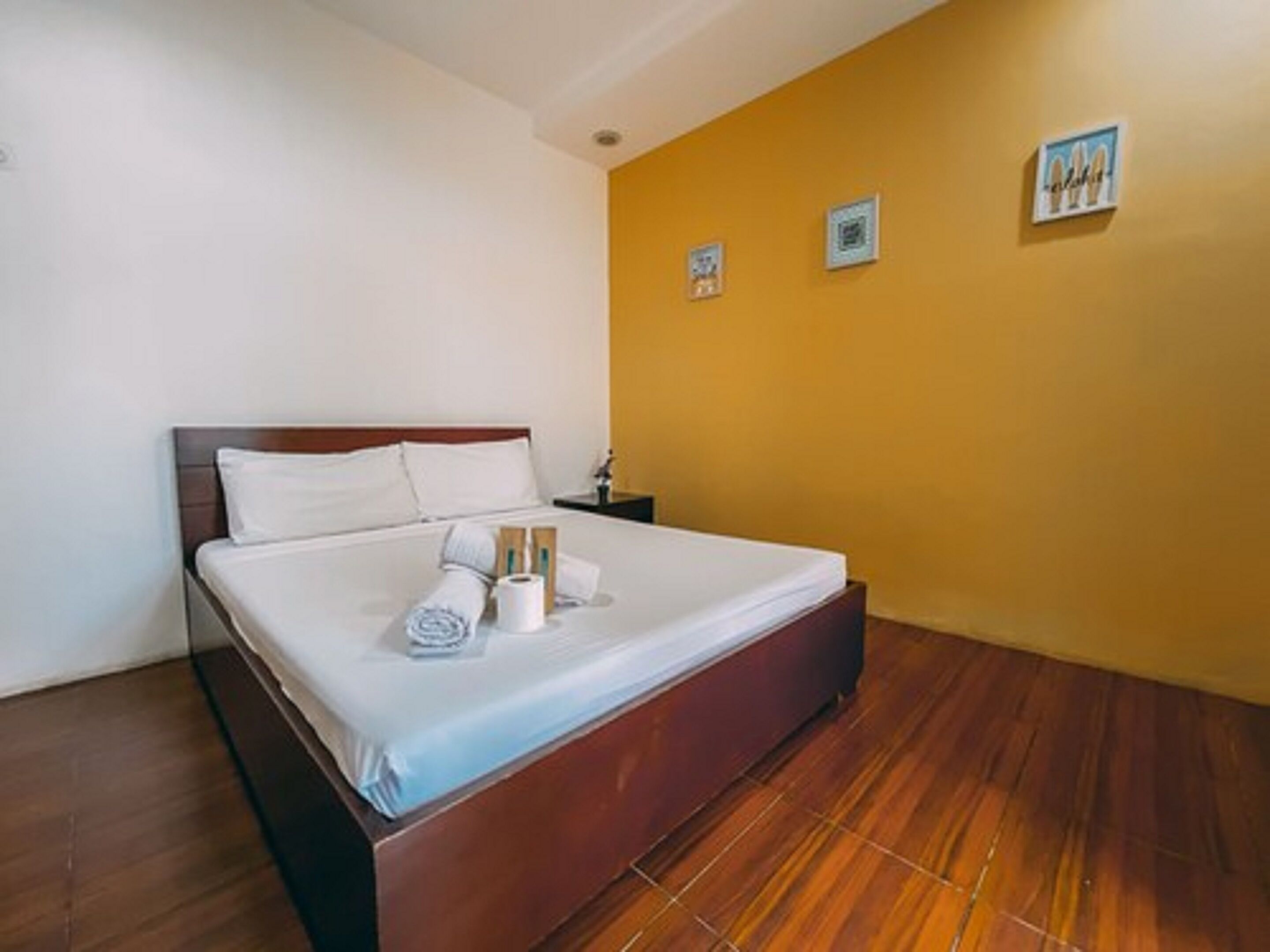 A neatly made bed with white linens, a wooden headboard, and a small bedside table with a lamp.