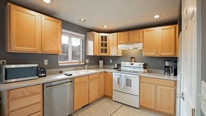 Una cocina compacta con armarios de madera, microondas, lavavajillas y estufa.