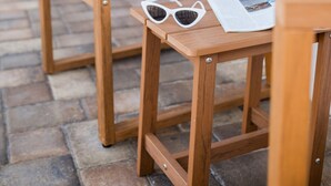 A wooden chair with a striped pillow and sunglasses on a table, outside a building with green and white walls. - 119 · ☀Pool✔ Kitchen✔ Beach✔ Self Checkin✔ Free Parking✔ (Clearwater)