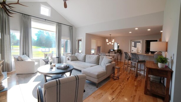 Un salón espacioso con un sofá grande, una mesa de centro y una zona de comedor con una cocina al fondo.