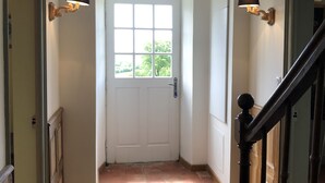 A hallway with a white door, two wall-mounted lamps, a wooden staircase, and a brown carpet. - 19th century residence - Alpes Mancelles (Rouessé-Vassé)