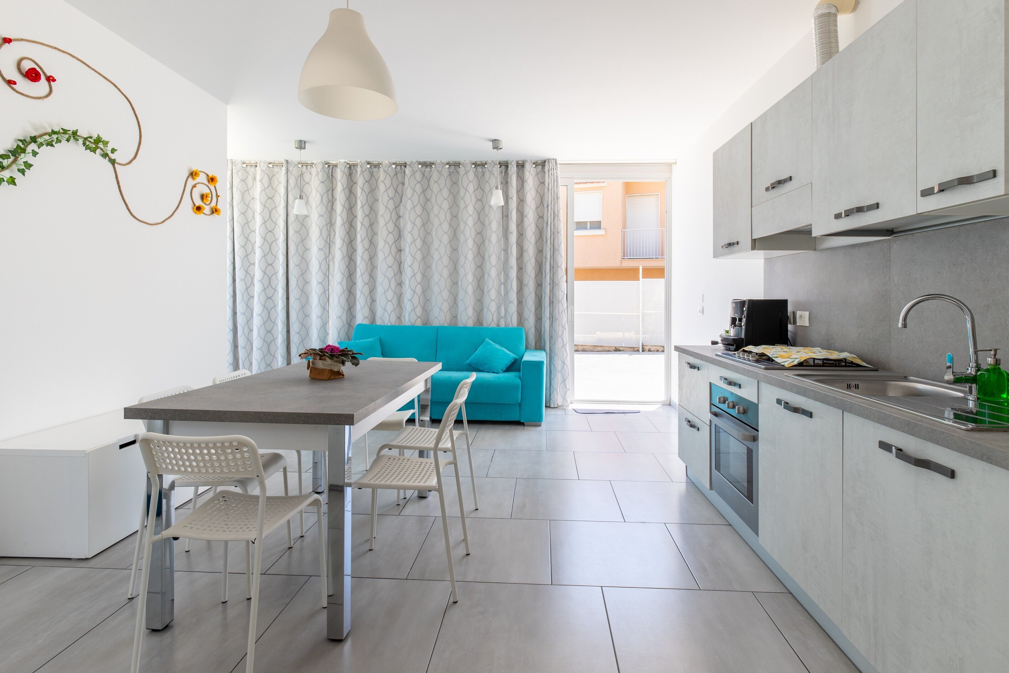 A modern kitchen with a dining area, a blue sofa, and a view to the outside.