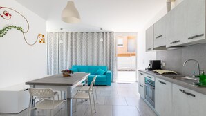 A modern kitchen with a dining area, a blue sofa, and a view to the outside.