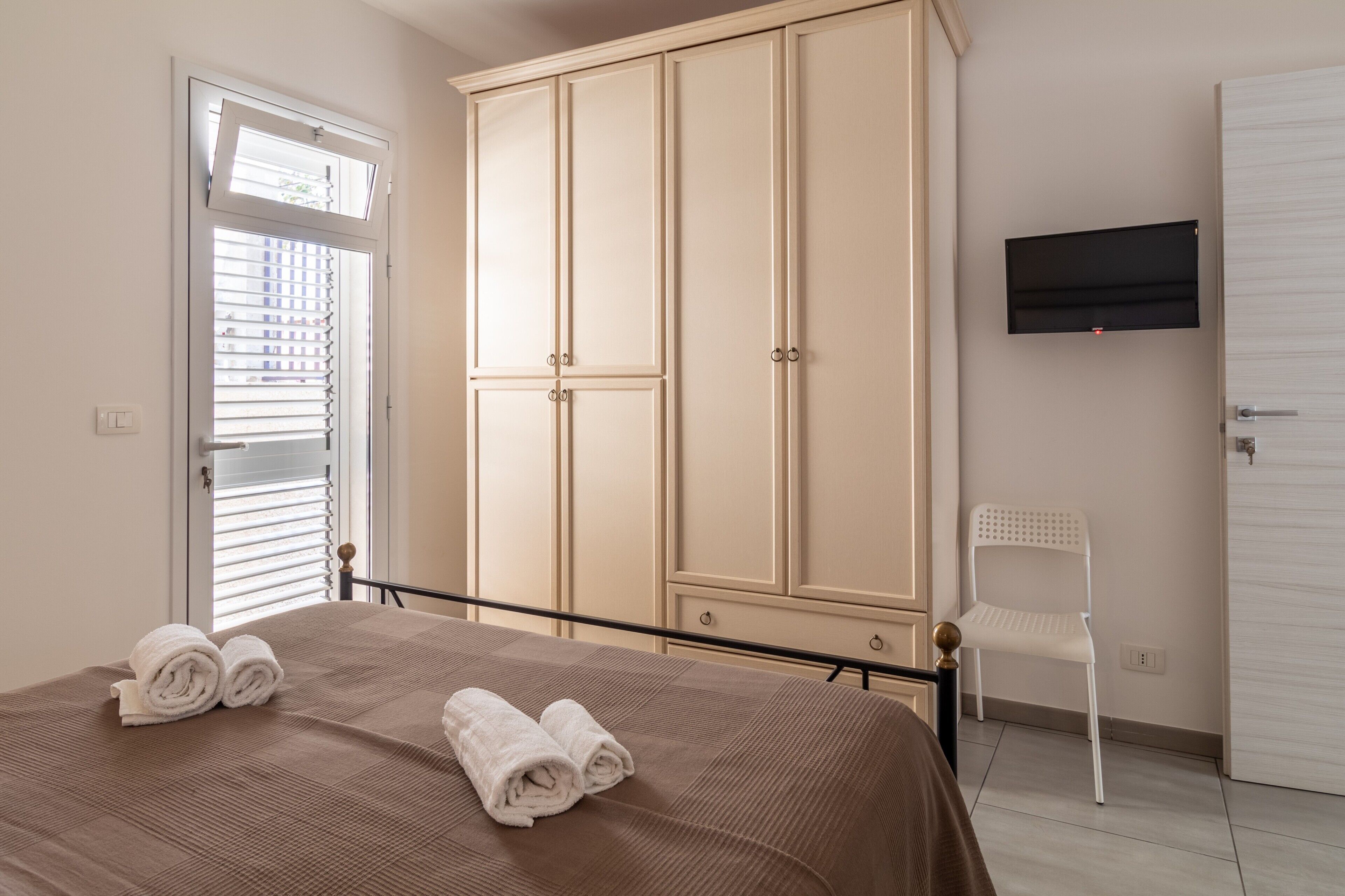 Une chambre à coucher avec un lit, une armoire, une chaise et un téléviseur.