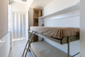 Ein Schlafraum mit Etagenbetten, einem Kleiderschrank und einem Badezimmer mit Duschvorhang.