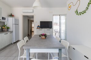 Eine moderne Küche mit Essbereich, einem Flachbildfernseher und einem großen Fenster.