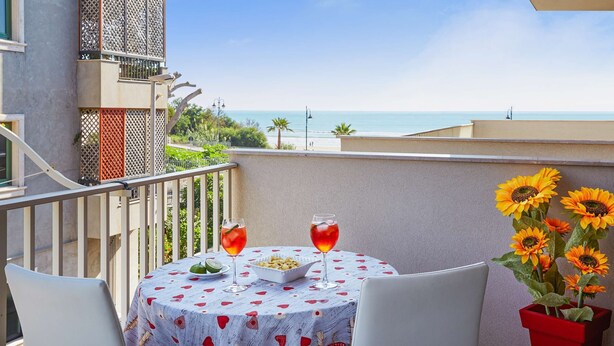A balcony with a table, two drinks, a bowl of food, and sunflowers.