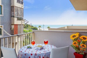 Un balcon avec une table, deux boissons, un bol de nourriture et des tournesols.