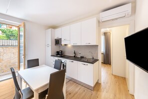 Una cocina moderna con armarios blancos, encimera negra y microondas integrado.
