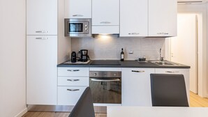 A modern kitchen with white cabinets, a built-in microwave, a coffee maker, and a sink. - Holiday Apartment 'New Casa Ilaria' near Center with Garden & Wi-Fi (Torri del Benaco)